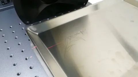 Precision MOPA fiber laser engraving a detailed floral design and custom text onto a stainless steel tray.