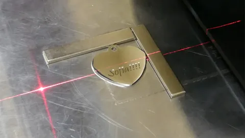 Industrial fiber laser engraving detailed custom typography and graphics onto round and heart-shaped metal charms.