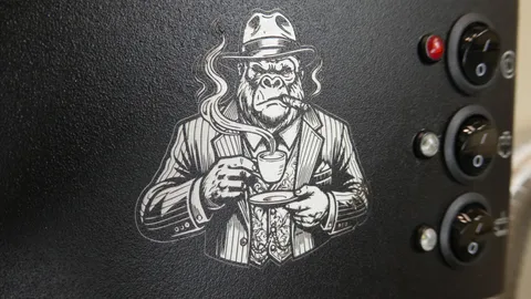 Macro detail of a precision fiber laser engraved gorilla mascot logo on a black textured metal control panel.