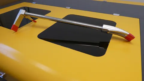 Heavy steel Halligan bar resting on a yellow industrial laser engraving workstation before custom marking.